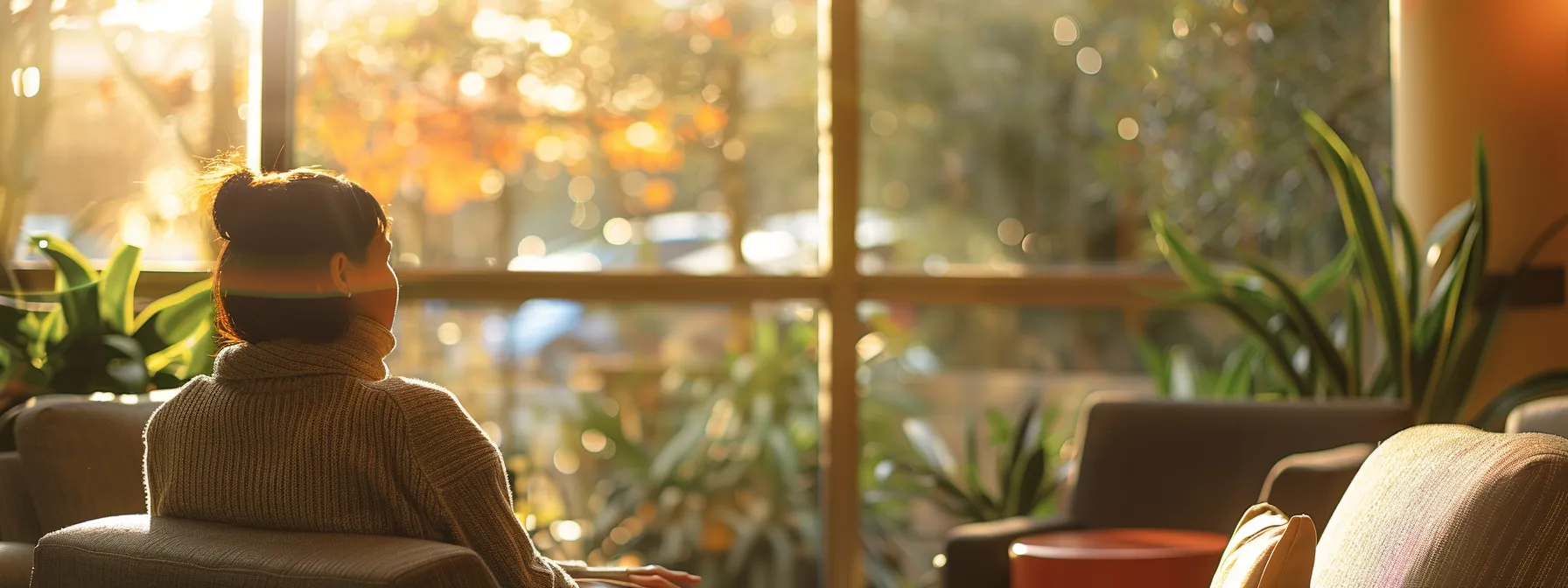 a warm-toned, inviting therapy room filled with soft lighting and comfortable seating, featuring a thoughtful individual gazing out of a window, reflecting on their journey through seasonal affective disorder and mental health recovery.